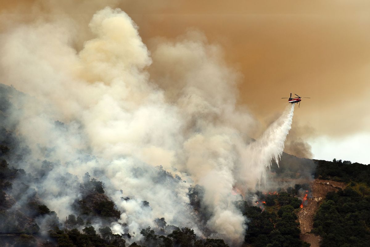 A firefighting helicopter performs a water drop as the Lake Fire burns in Los Padres National Forest with evacuation warnings in the area on July 6, 2024 near Los Olivos, California. (Mario Tama/Getty Images)