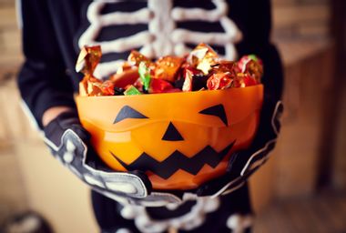 Boy in skeleton costume holding bowl full of candies